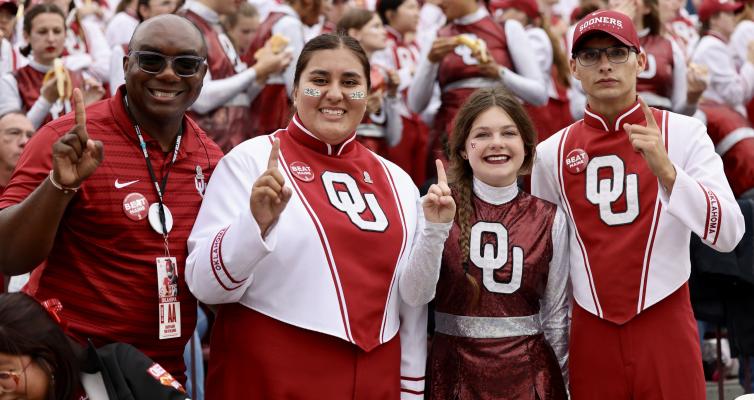 FORMER HOLDENVILLE GOLDEN PRIDE BAND DIRECTOR, CHAUVIN AARON, IS THE CURRENT DEVELOPMENT OFFICER FOR UNIVERSITY BANDS AT THE UNIVERSITY OF OKLAHOMA. Aaron paused for a picture with these members of the Pride of Oklahoma from Holdenville. Pictured are Chauvin Aaron, Eliza Maylen, Sara Coats and Mayson Carpitcher.