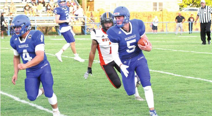 Holdenville running back # 4, Christian Zambrano, clears the way for # 5, Cy Tiger, as Holdenville quarterback # 2, Matt Cox, looks on. Wewoka defeated the Wolverines in a hard fought season opener.