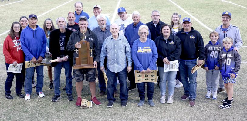 HOLDENVILLE HIGH SCHOOL HONORED THE SCHOOL’S 1964 SATE CHAMPIONSHIP TEAM PRIOR TO THE WOLVERINES’ DISTRICT WIN OVER DAVIS FRIDAY NIGHT. Team Members and family members representing the players attending were: Tammy Valley (Daughter of Granville Turner), Melinda Harjo (Daughter of Lenard Harjo), Gene Harjo, Annja Turner (Daughter-in-law of Granville Turner), Joe Brawley, Ricky Turner (son of Granville Turner), Jerry Moeller, Ronnie Lee (holding the trophy), Tom Turner, Trent Hodgins, Gene Hadley, Bruce Foste