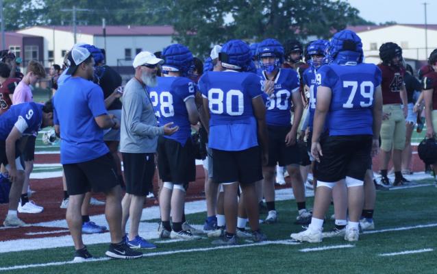 HOLDENVILLE COACHES, TYSON JONES AND DARIN JOHNSON gave the football team some instructions during a timeout at the Atoka Football Camp. The coaches are expecting the Wolverines to be improved over last year.