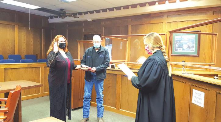 Judge Smith swears in new Hughes County Clerk, Angela Brooks with Buford Johnson (dad) holding the Bible for her.