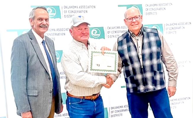 The Oklahoma Association of Conservation Districts honored Leon Barrett (center) for 10 years of service with the Hughes County Conservation District.