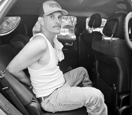 Above, Michael Calvert sits handcuffed in a law enforcement vehicle after being arrested Saturday morning in Wewoka. Calvert was wanted in connection with a July 5 stabbing in Hughes County. (Photo courtesy District Attorney’s Office).