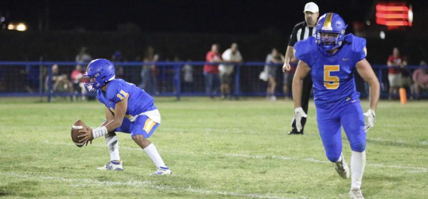 Holdenville quarterback # 11, Izaia King, handles the snap from center while # 5, Cy Tiger, prepares to clear the path of defenders. Holdenville and Davis both scored 4 touchdowns but Davis converted more points after touchdowns to edge the Wolverines 32-26.