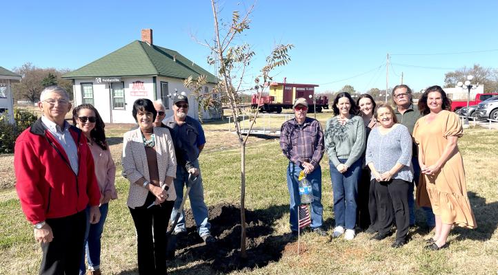 MEMBERS OF THE HOLDENVILLE CHAMBER OF COMMERCE GATHERED AT HOLDENVILLE TRAIN DEPOT recently to plant a tree in honor of the 125th anniversary of Holdenville’s founding. Pictured above are Jack Bush, Amanda Estala, Tonja Weaver, City Manager Larry Mitchell, Cameron Miller, Randy Case, Jessica Beck, Breana Hester, Roberta Davis, Andy Massey, and Amber Gassaway.