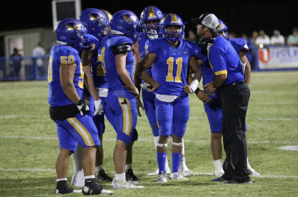 Holdenville Wolverine Head Coach, David Barker, gives instructions to his offense during a time out in the Wolverines thrilling 22-20 win over Atoka. Holdenville quarterback # 11, Izaia King, running back # 9 Cash Carter and lineman # 50, Julius Jackson and other Wolverines listen intently as Couch Barker gives instructions