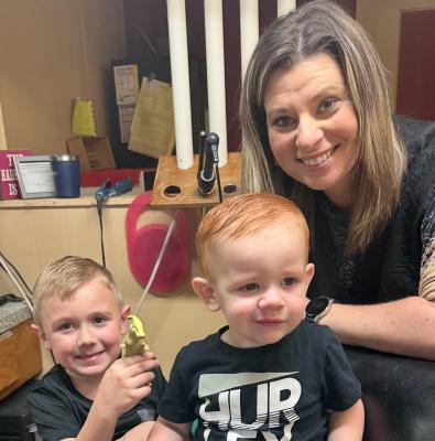 Baby Nathaniel gets his very first haircut by Misti O’Kelley as brother Ransom offers some comfort with his toy dinosaurs