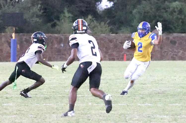 Holdenville running back # 2, RJ Lowe, cuts away from two Tiger defenders in the Wolverines’ 62-20 victory over the Wewoka Tigers